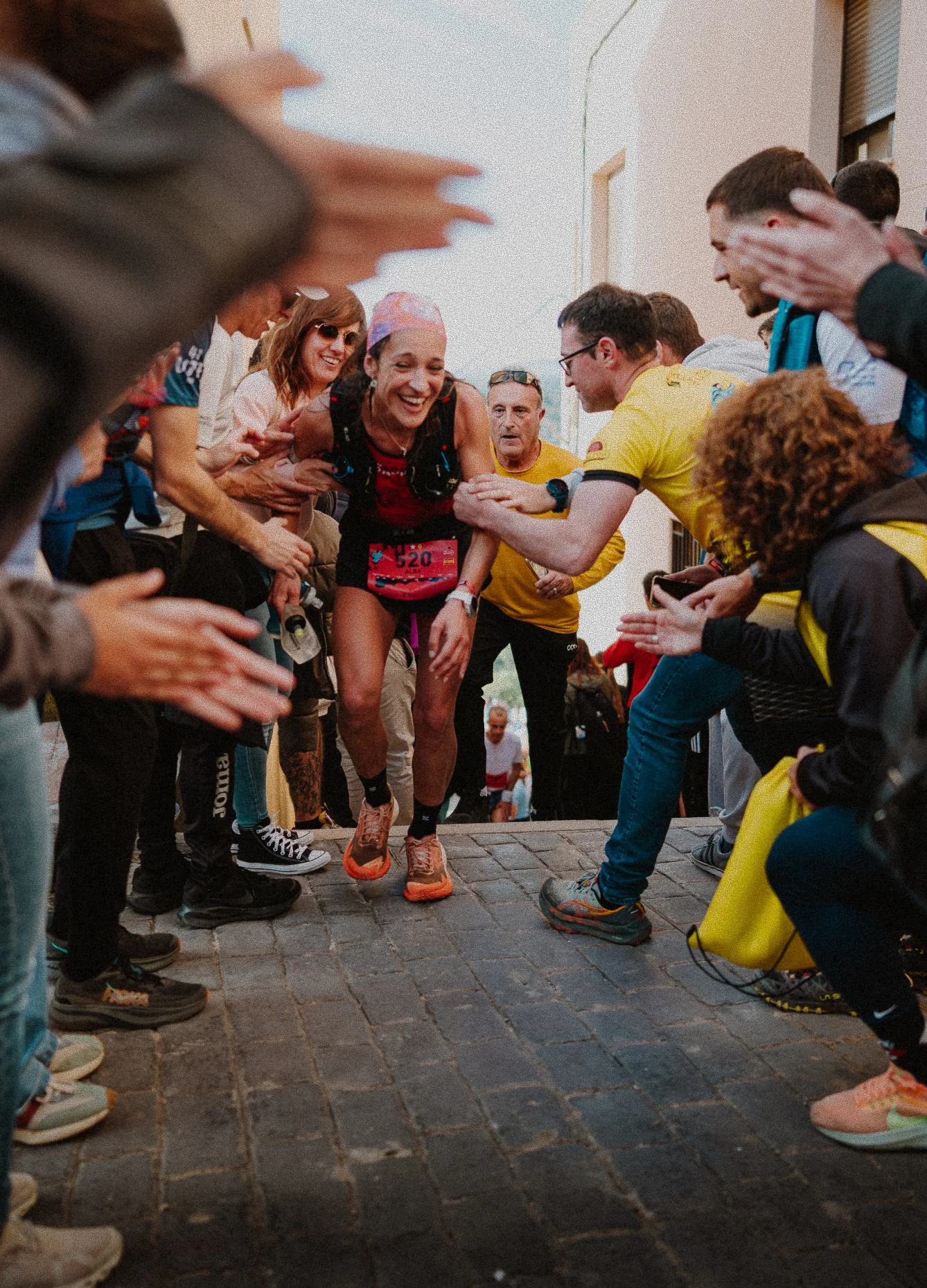 Corredora atravesando un pasillo de público que la anima en un pueblo