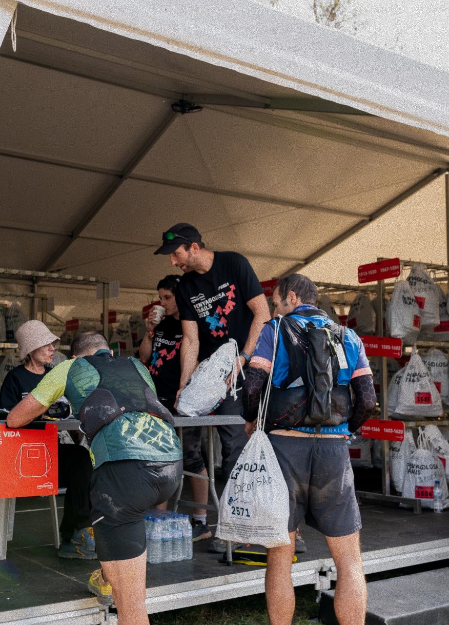 Voluntarios atendiendo a corredores bajo una carpa de avituallamiento